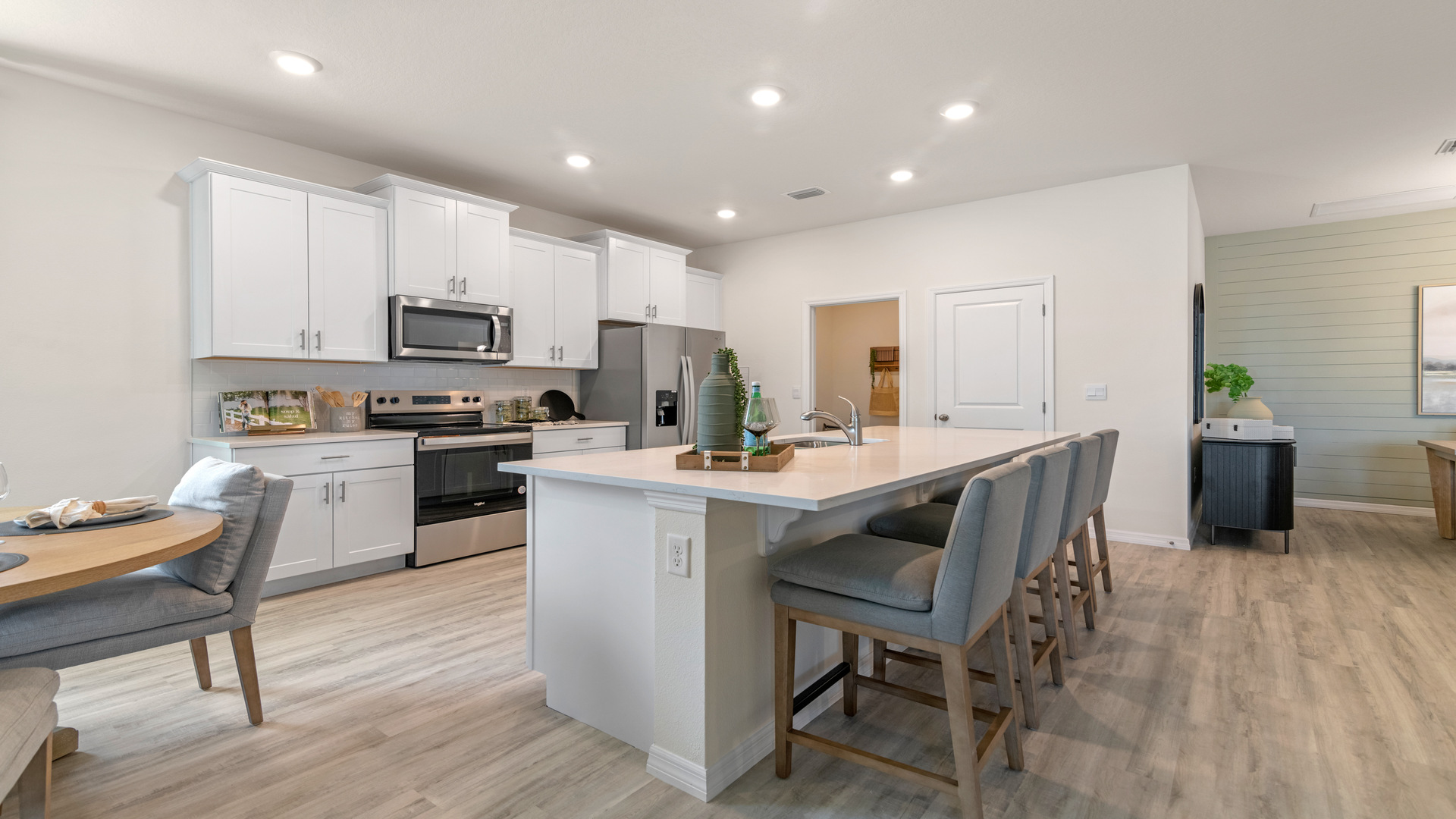Kitchen with island seating, quartz counters, spacious pantry and stainless steel appliances.