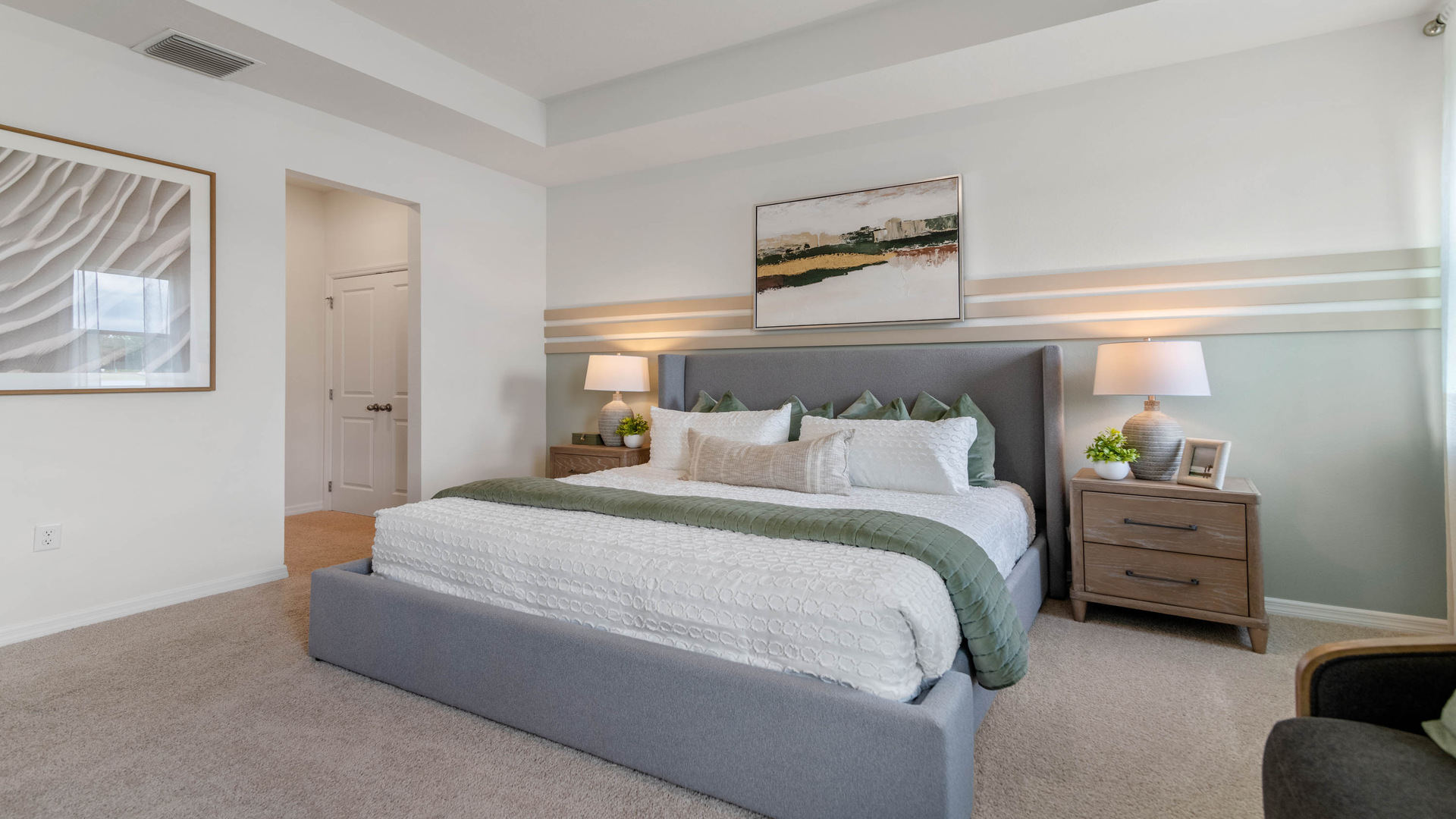 Spacious primary bedroom with king size bed, carpet flooring, natural lighting and a walk in closet.