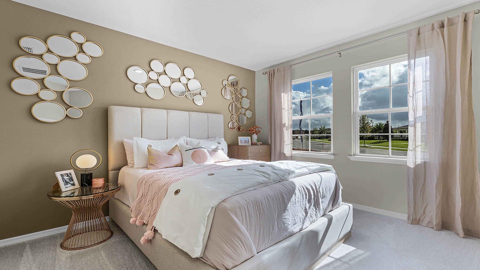 Spacious primary bedroom with king size bed, carpet flooring, natural lighting.