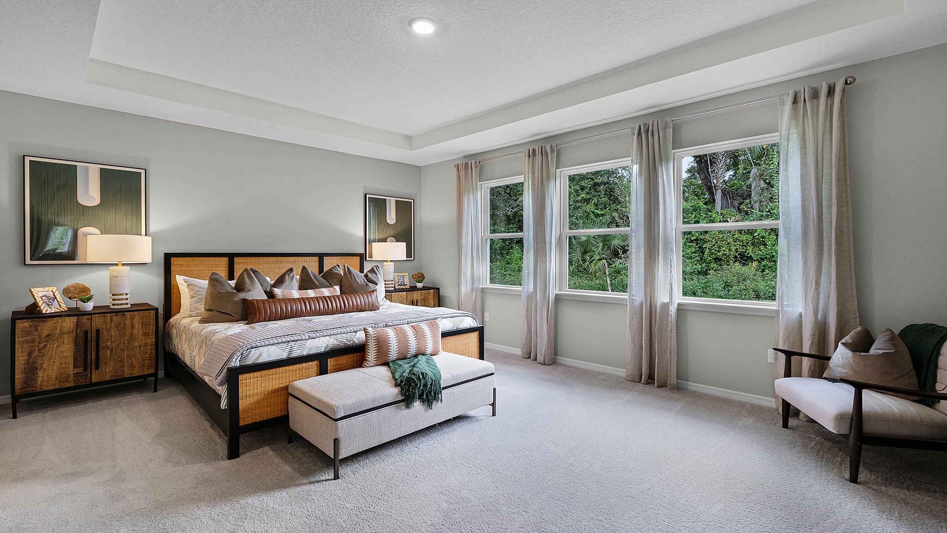 Spacious primary bedroom with king size bed, carpet flooring, natural lighting.