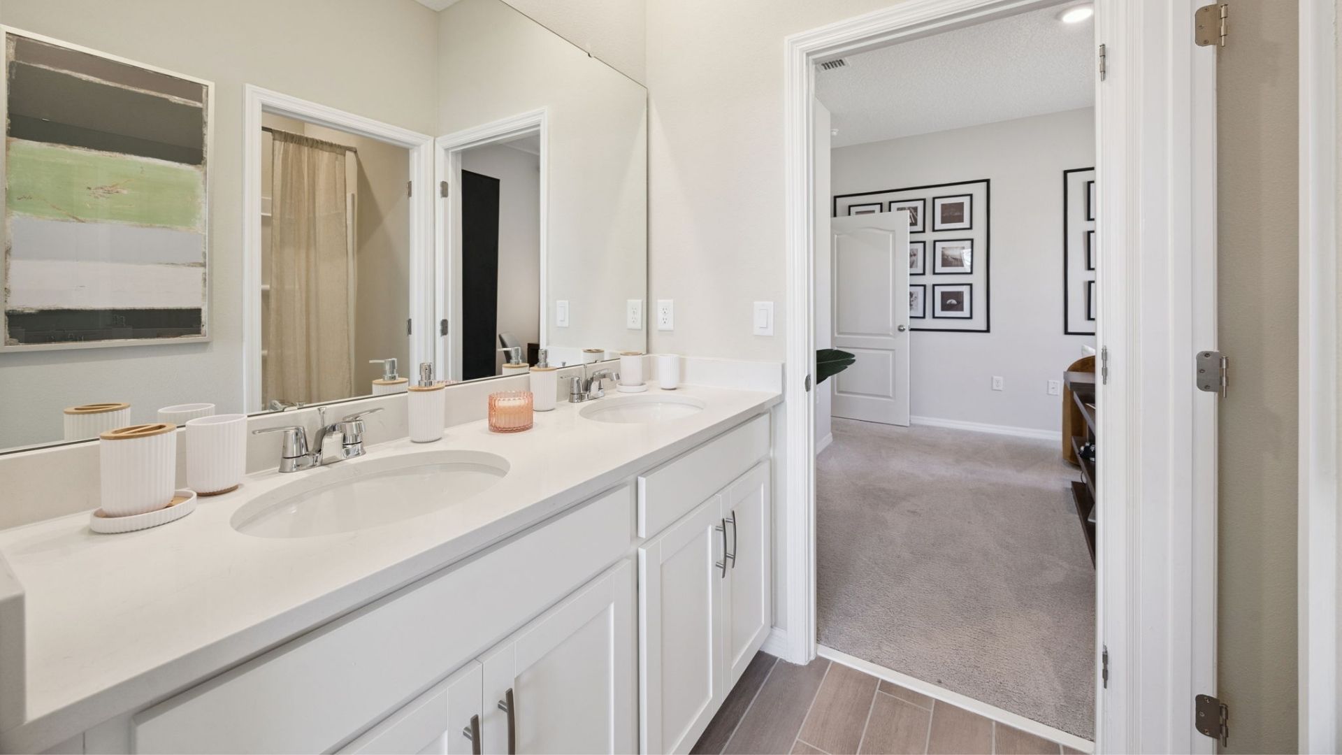 Modern primary bathroom with double vanity countertops with granite, cabinets and large wall mirror.