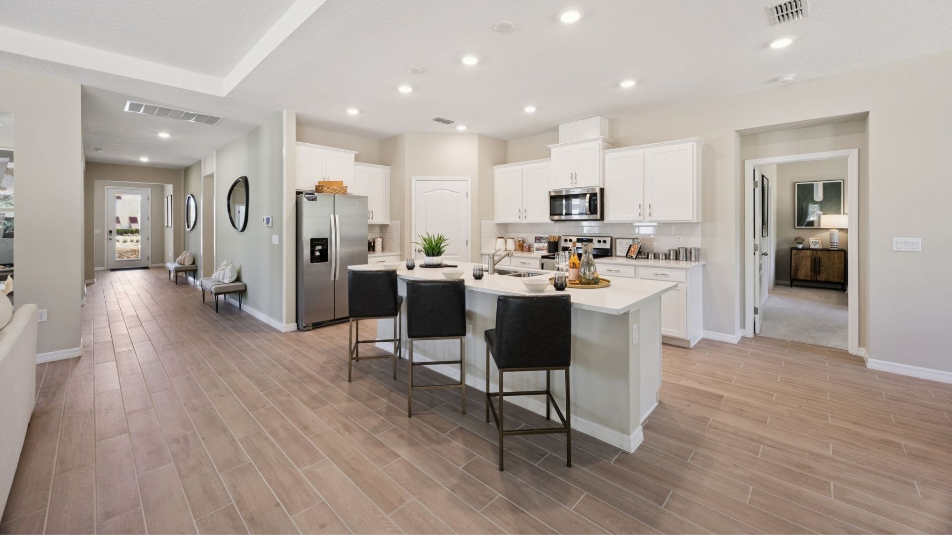 Kitchen with island seating, quartz counters, spacious pantry and stainless steel appliances.