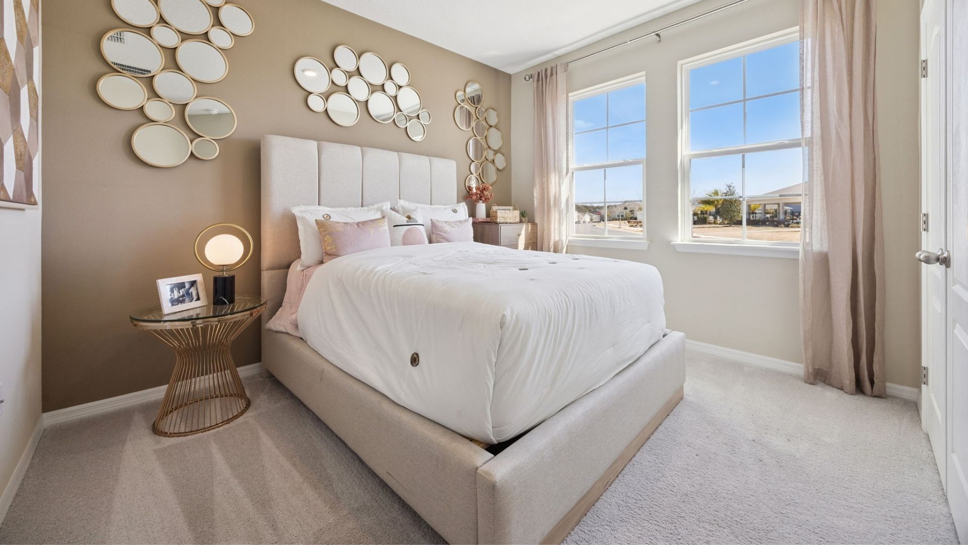 Spacious primary bedroom with king size bed, carpet flooring, natural lighting.