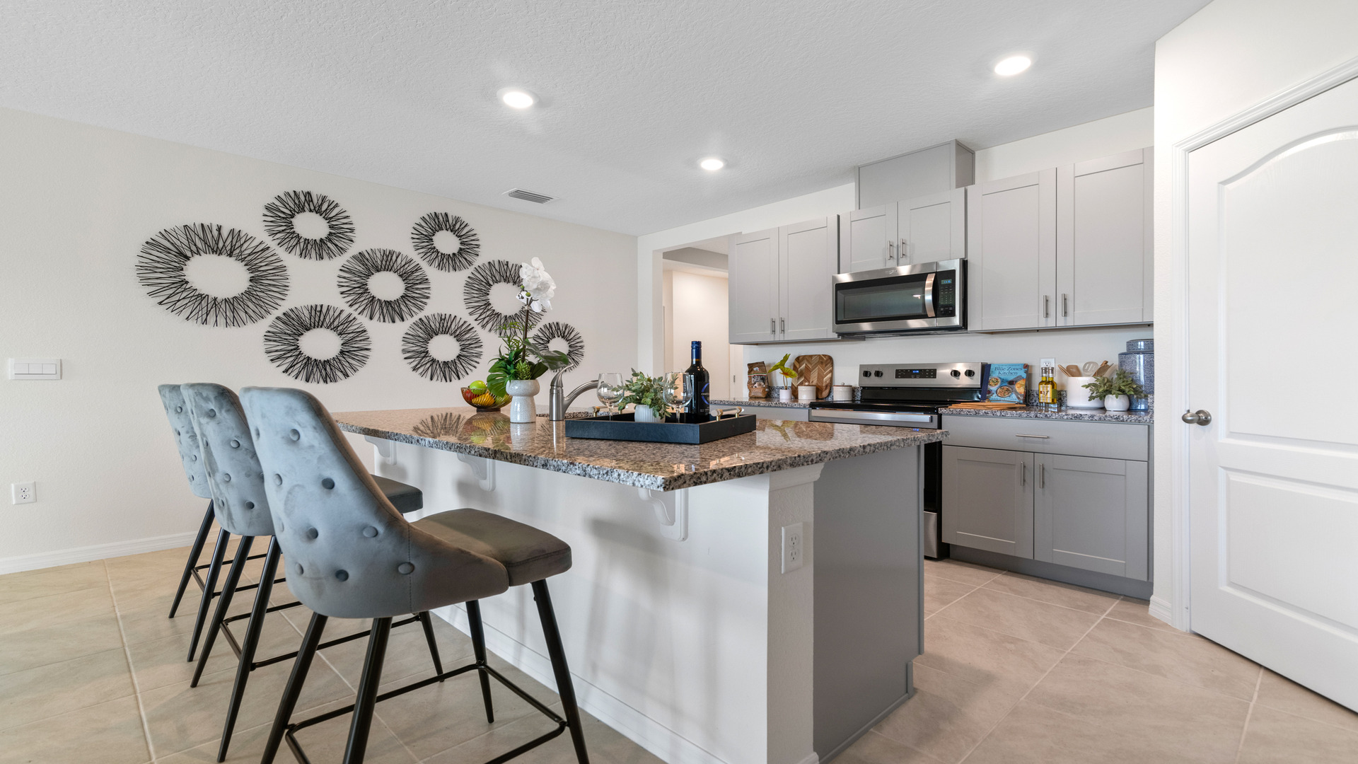 Kitchen with island seating, granite counters, spacious pantry and stainless-steel appliances.