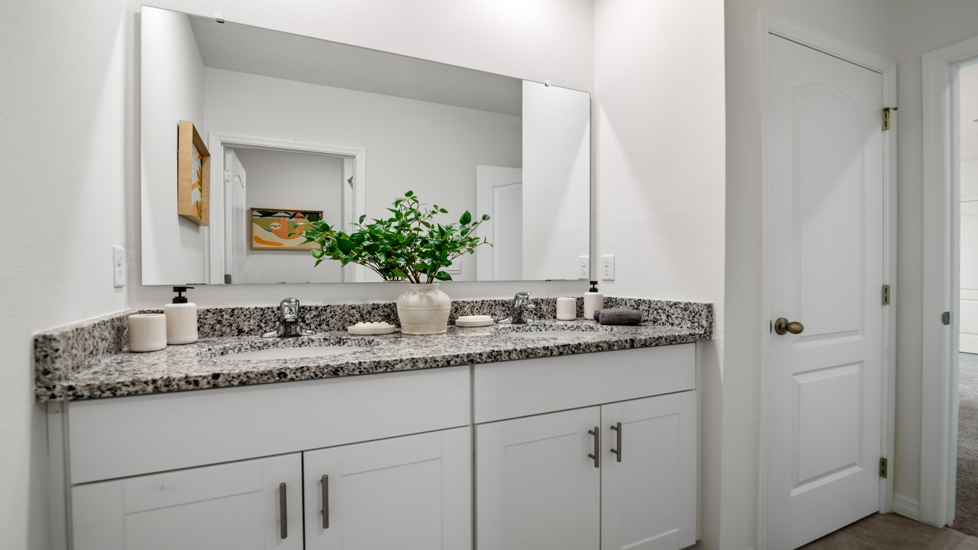 Modern bathroom with double vanity sinks, large wall mirror, cabinets and granite countertops.