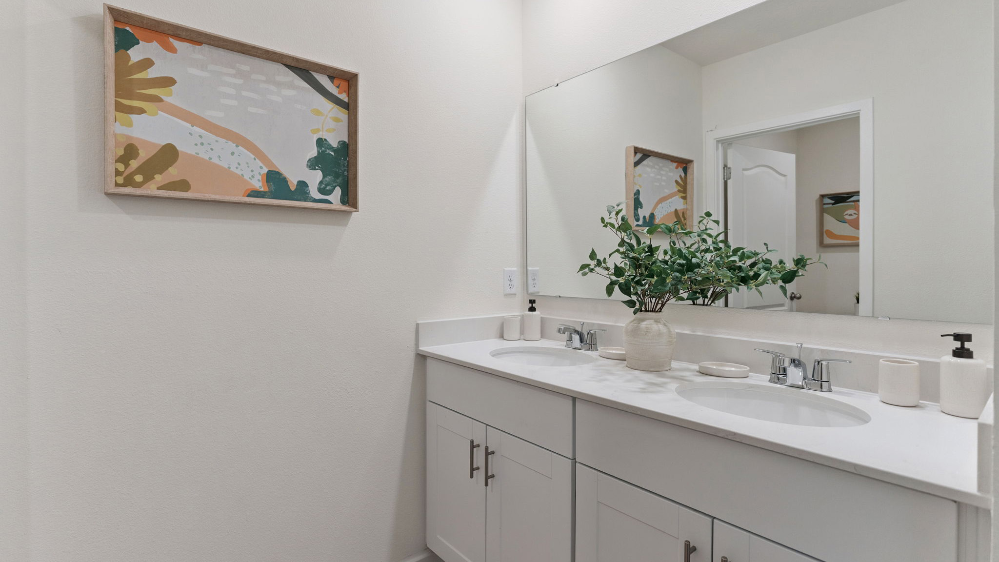 Modern bathroom with double vanity, large wall mirror, cabinets and quartz countertops along with walk-in shower
