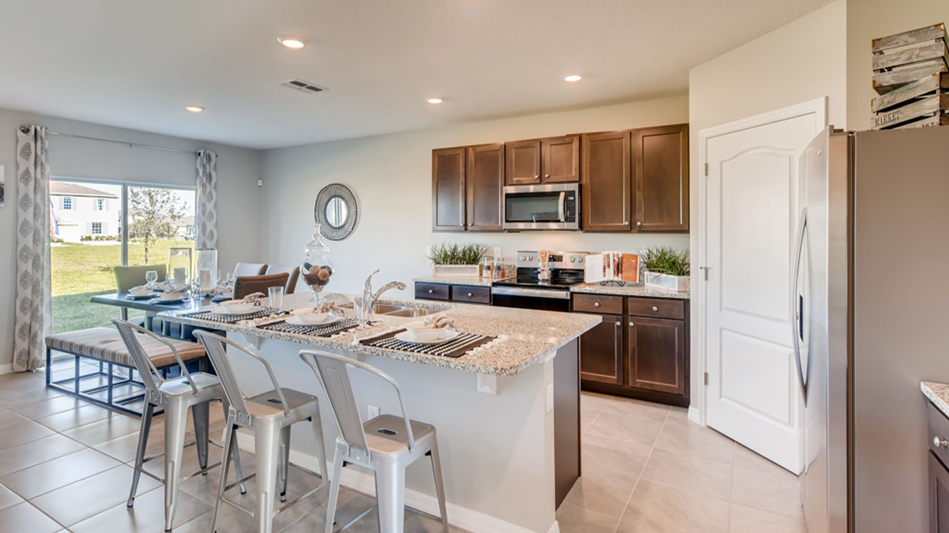 Kitchen with island seating, granite counters, spacious pantry and stainless-steel appliances.