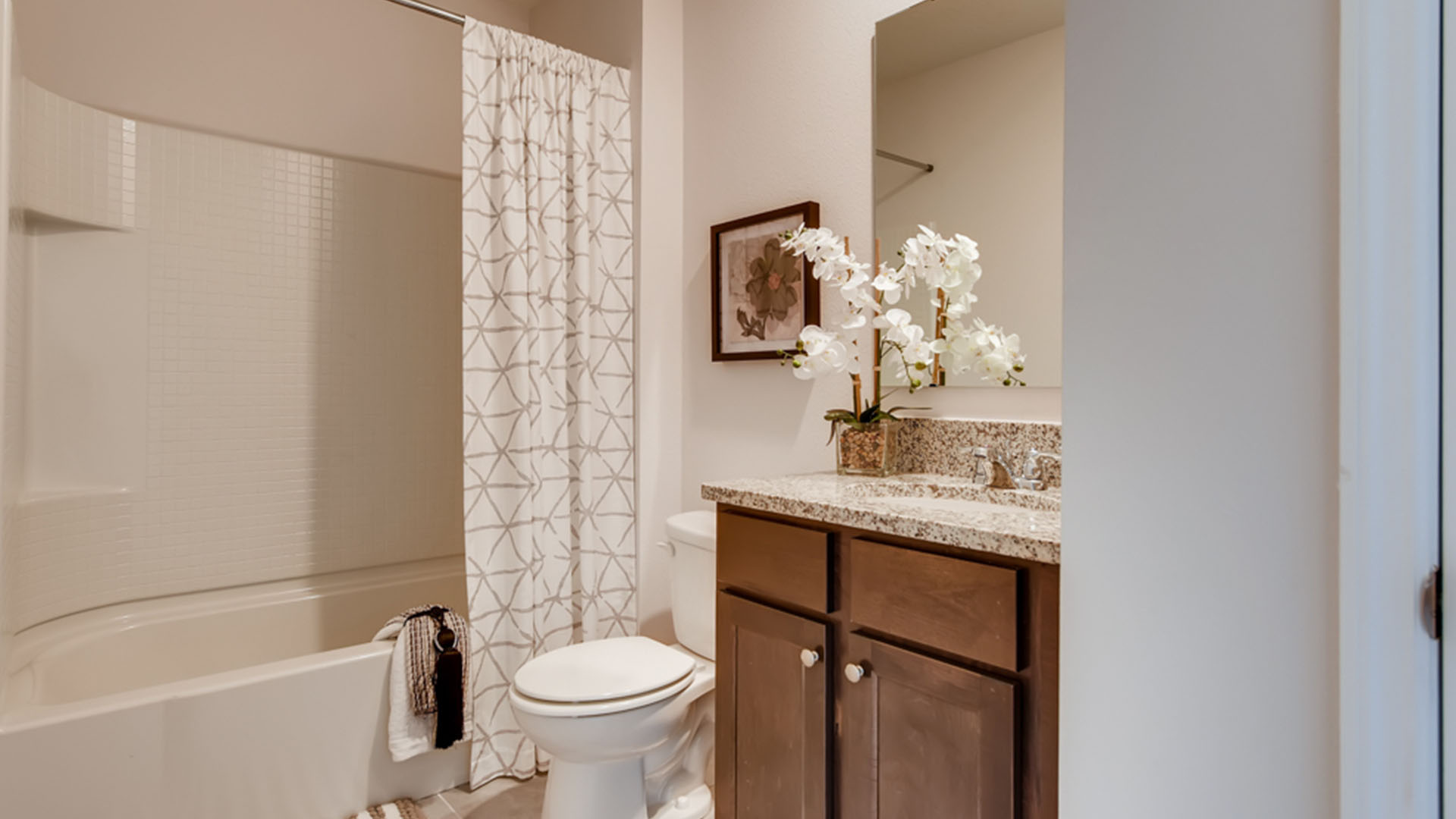 Modern bathroom with single bowl sink, granite vanity, wall mirror, cabinets and toilet.