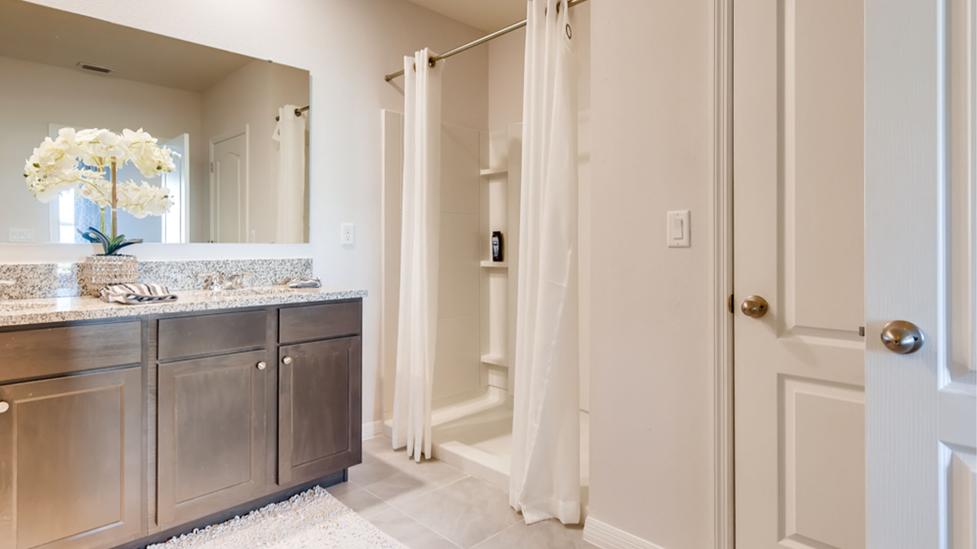 Modern bathroom with single bowl sink, granite vanity, wall mirror, cabinets and toilet.