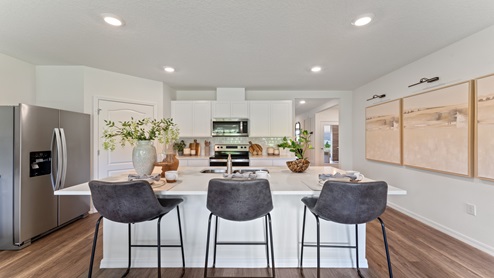 Kitchen with island seating, granite counters, spacious pantry and stainless-steel appliances.