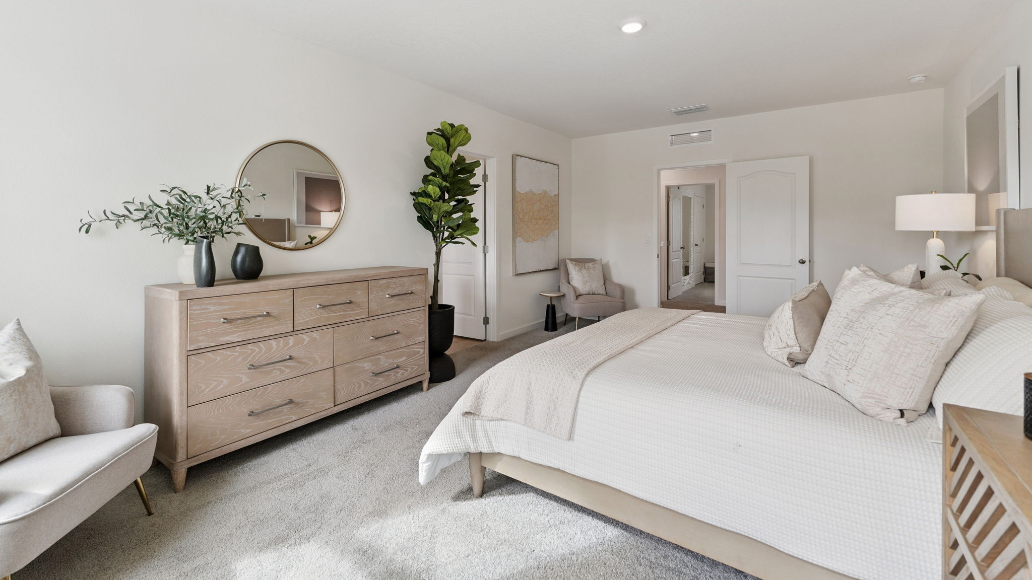 Spacious primary bedroom with king size bed, carpet flooring, natural lighting.