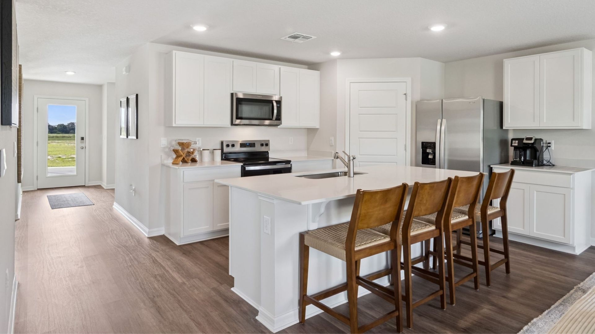 Kitchen with island seating, quartz counters, spacious pantry and stainless steel appliances.