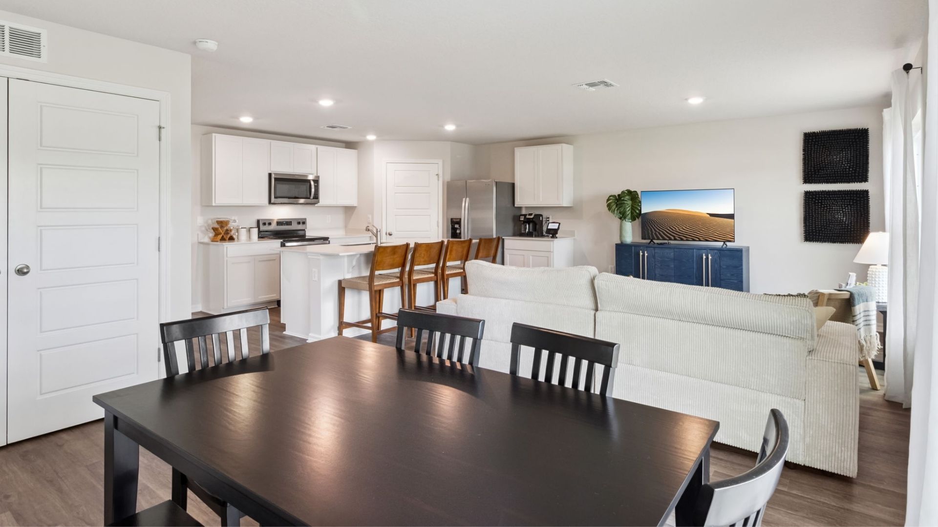 Kitchen with island seating, quartz counters, spacious pantry and stainless steel appliances.