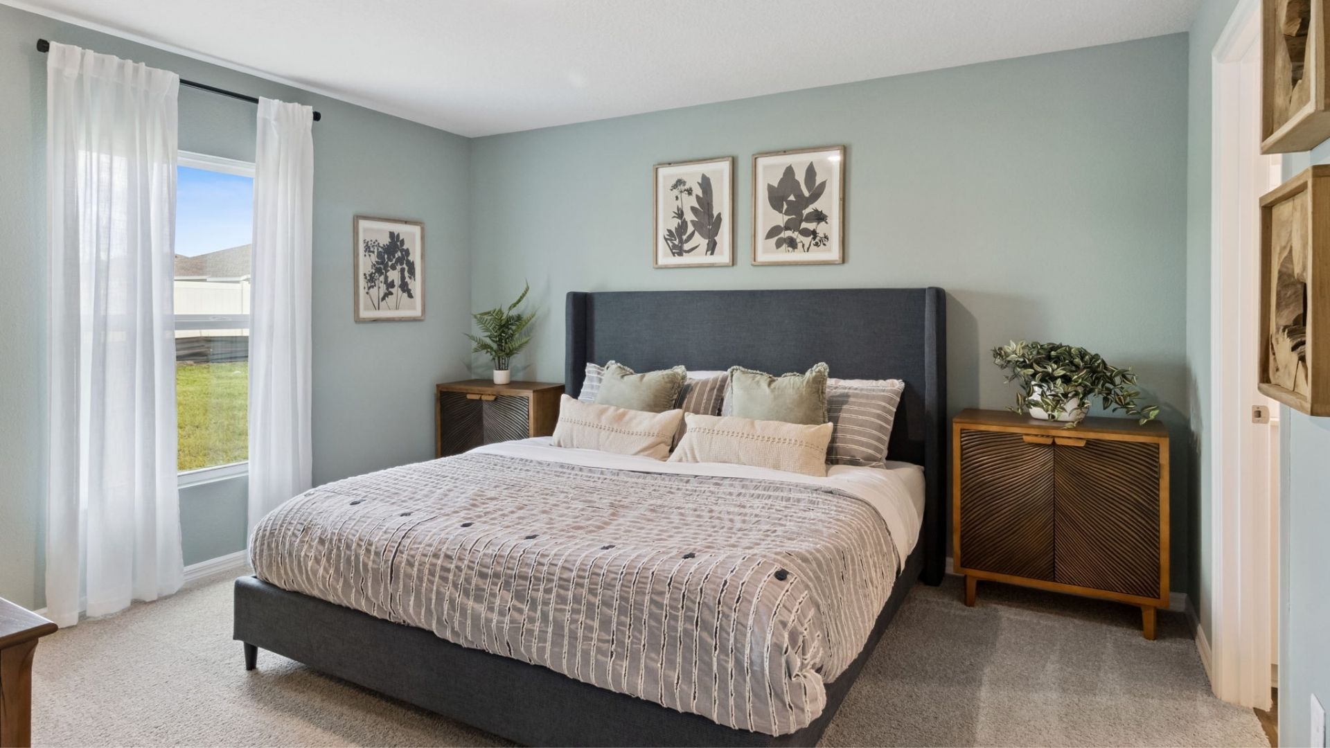 Spacious primary bedroom with king size bed, carpet flooring, natural lighting.