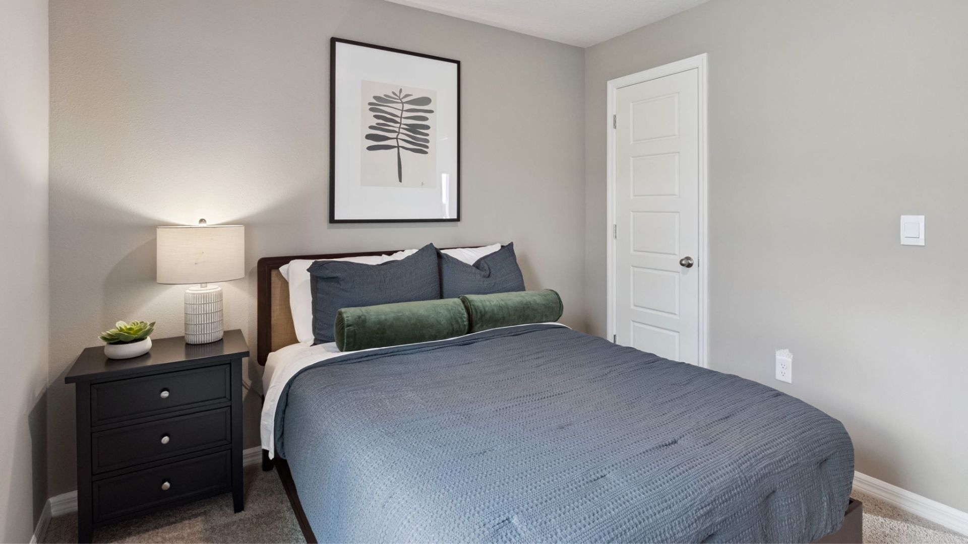 Spacious primary bedroom with king size bed, carpet flooring, natural lighting.