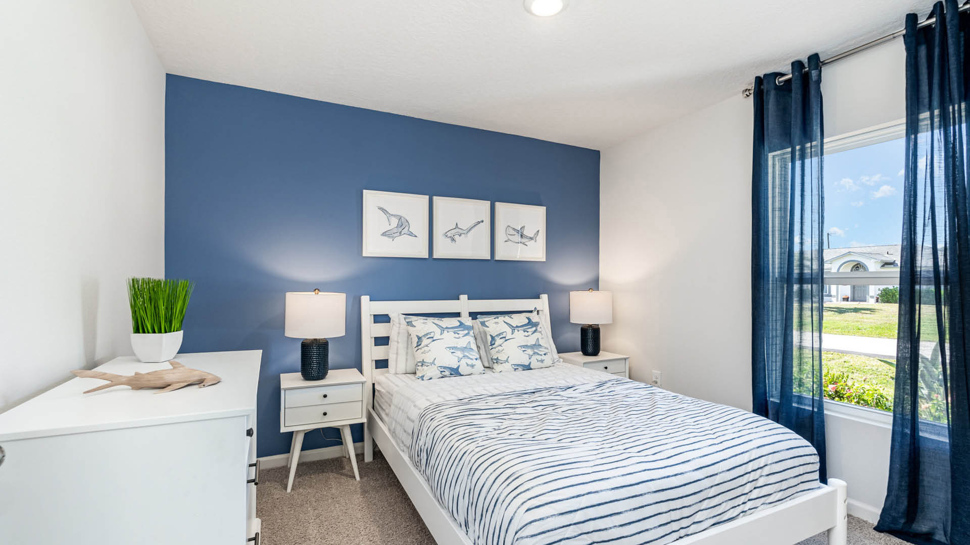 Spacious primary bedroom with king size bed, carpet flooring, natural lighting.