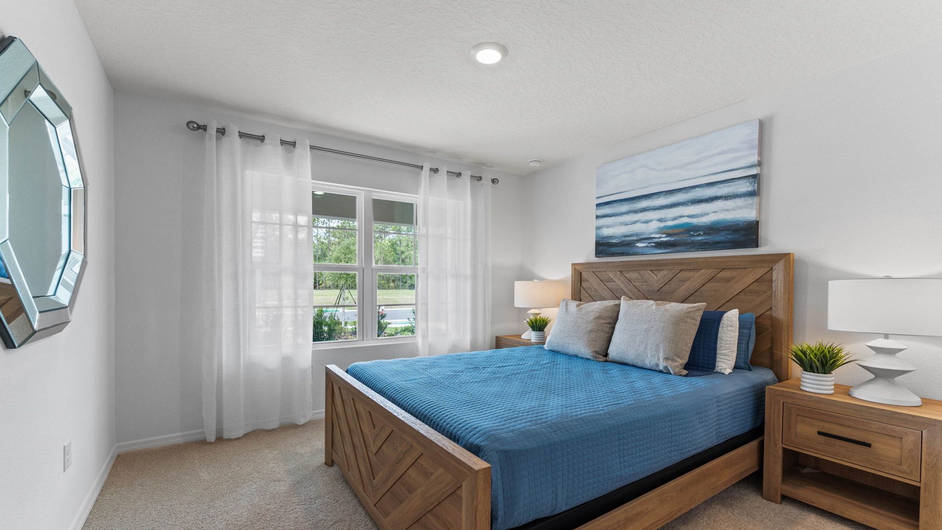 Spacious primary bedroom with king size bed, carpet flooring, natural lighting.