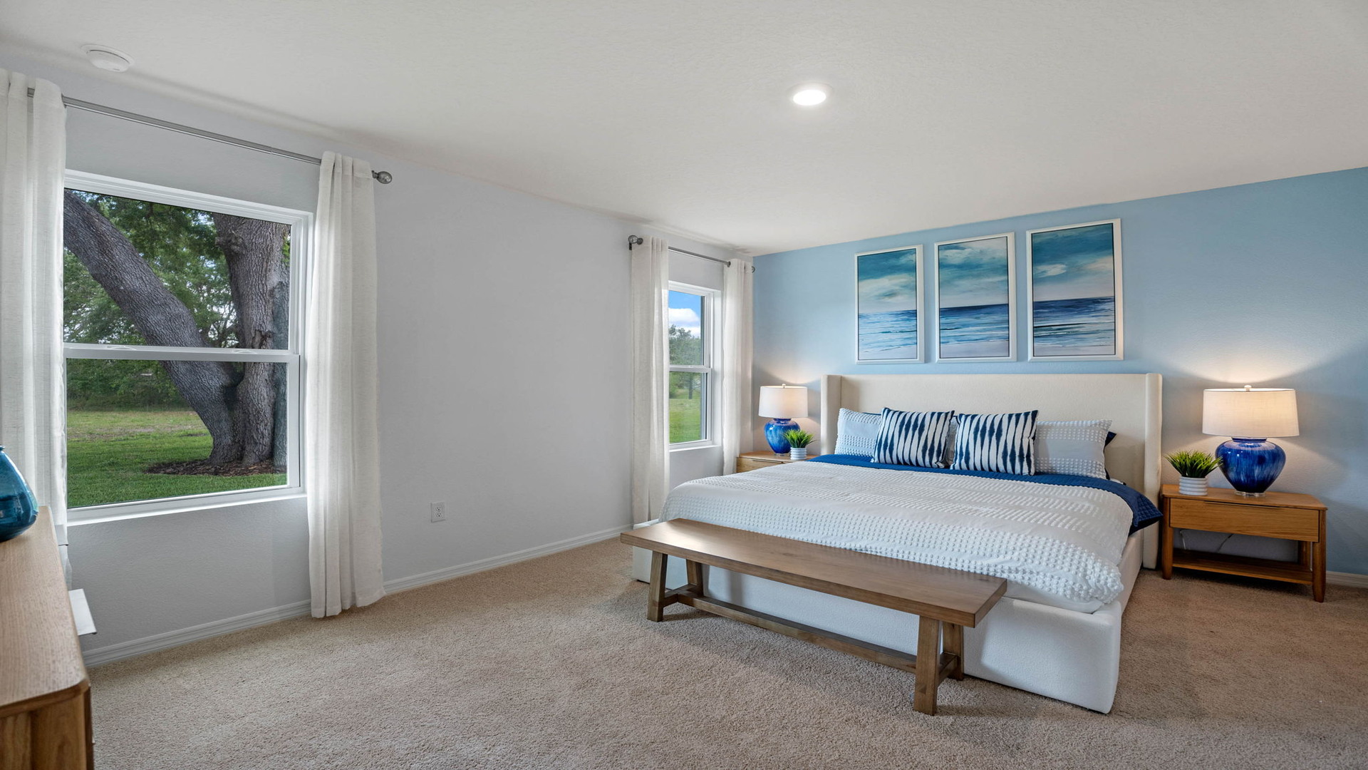 Spacious primary bedroom with king size bed, carpet flooring, natural lighting showing access to primary bathroom.