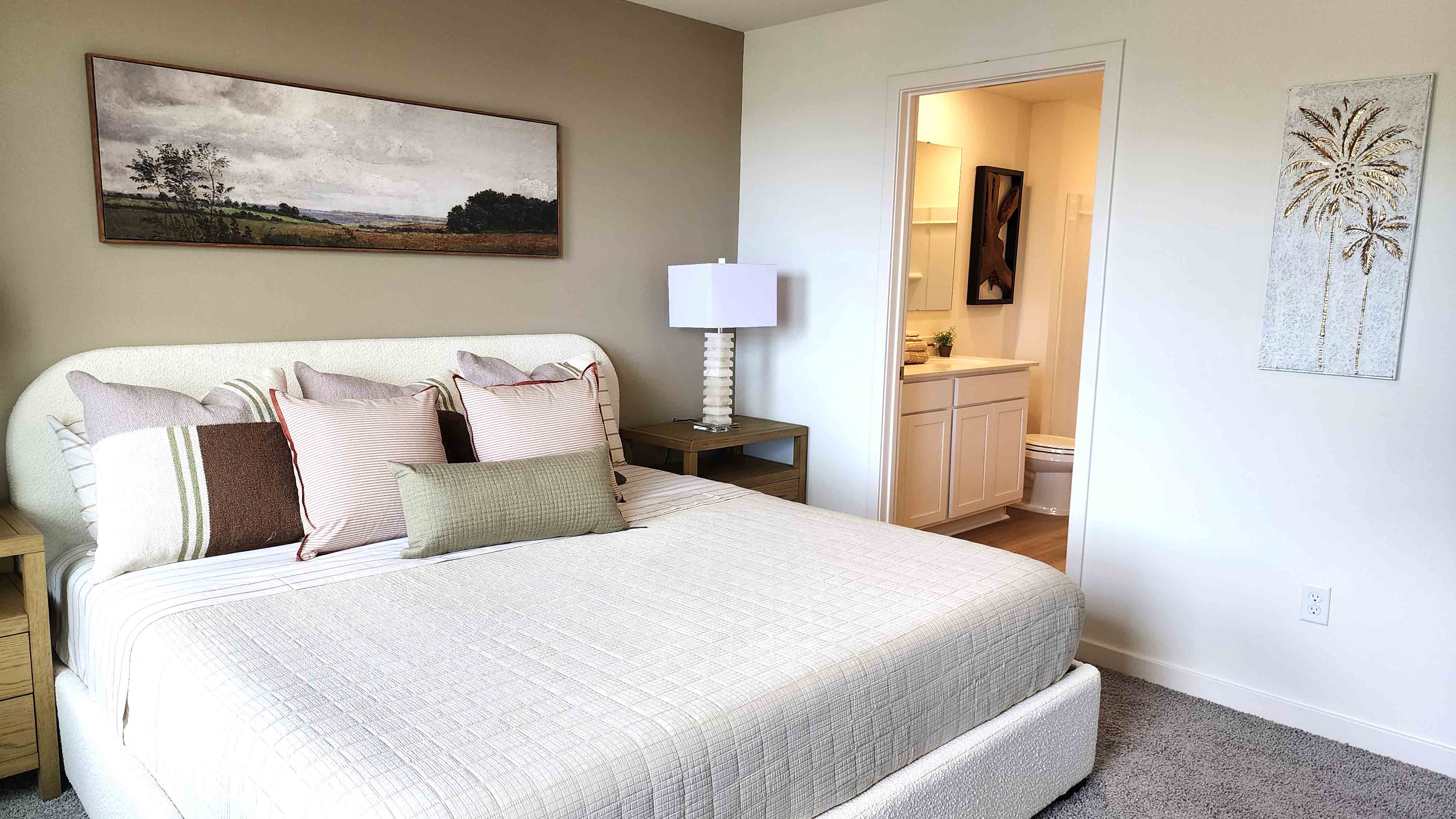 Spacious primary bedroom with king size bed, carpet flooring, natural lighting.