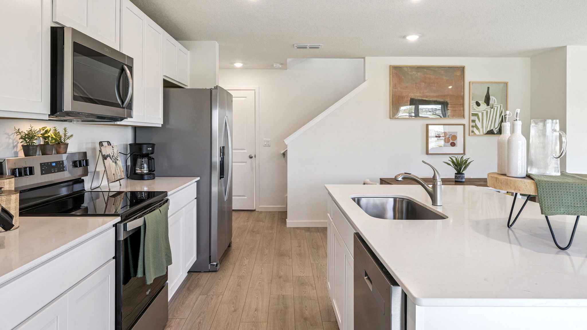Kitchen with island seating, quartz counters, spacious pantry and stainless steel appliances.