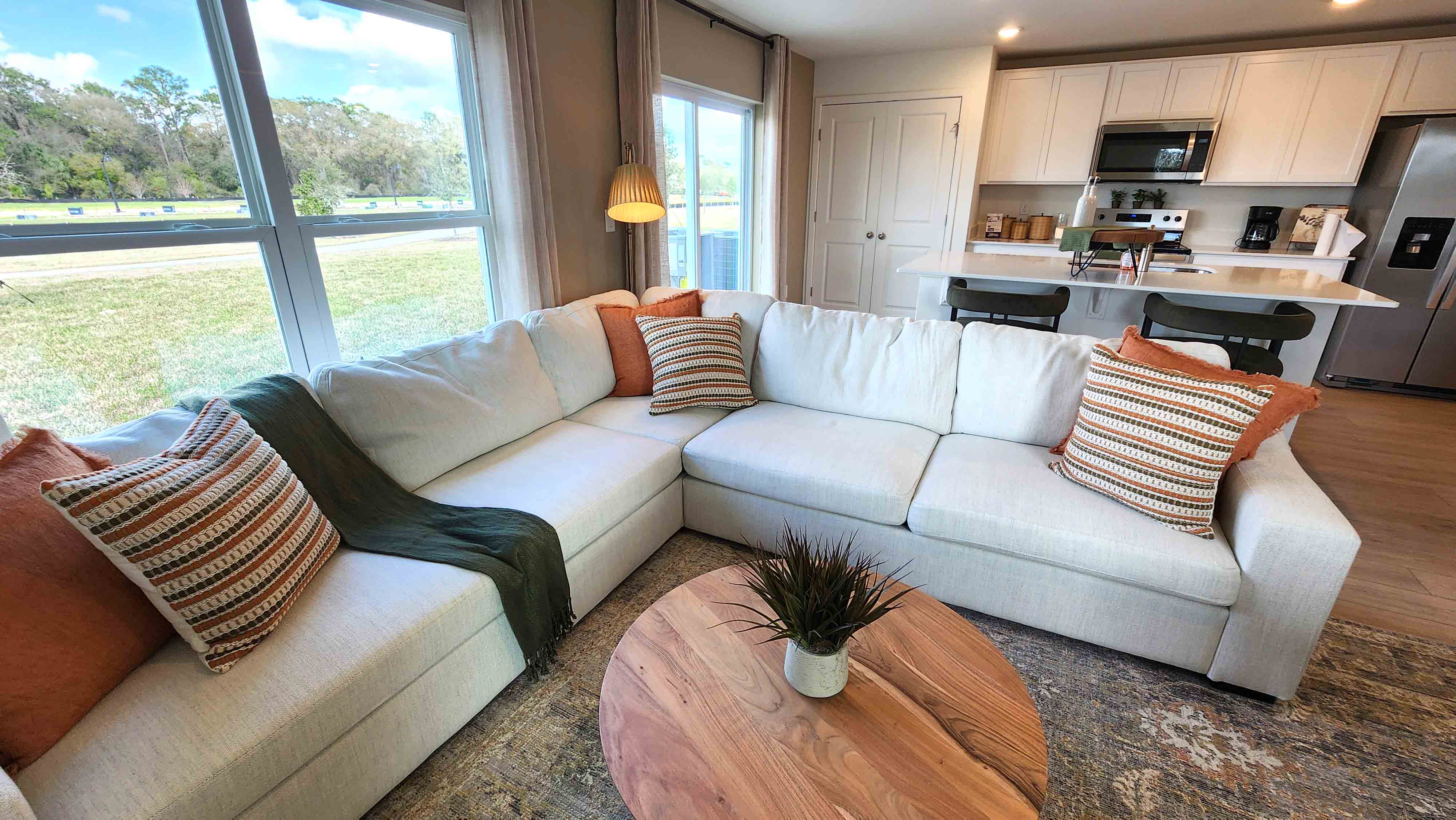 Living area with couch seating, entertainment system and natural lighting overseeing kitchen and dining room