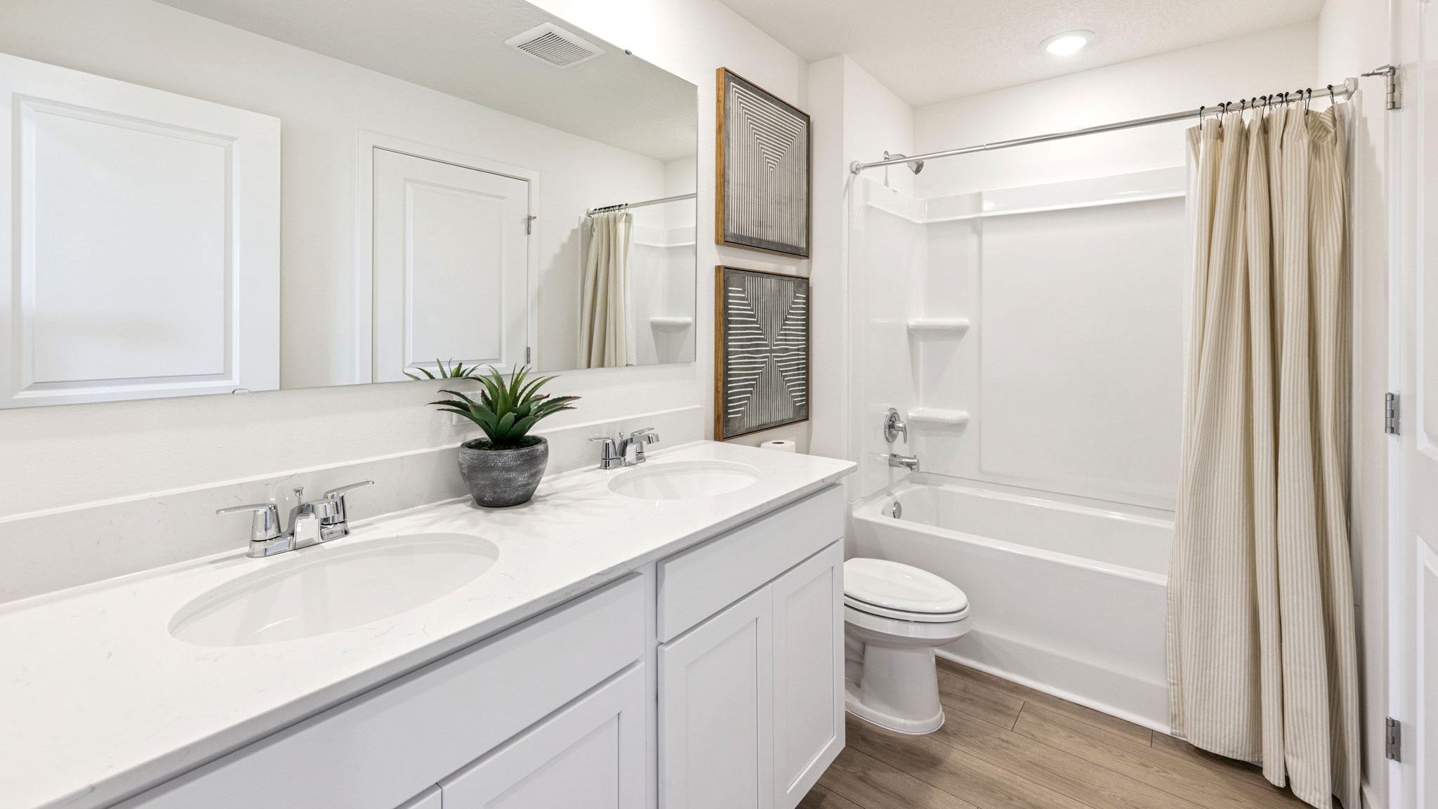 Modern bathroom with double vanity, large wall mirror, cabinets and quartz countertops