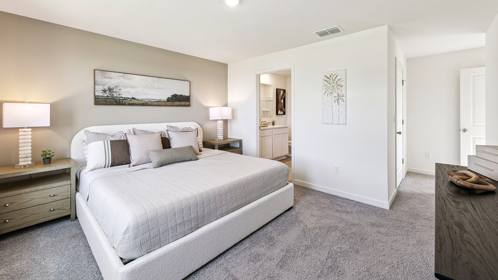 Spacious primary bedroom with king size bed, carpet flooring, natural lighting.