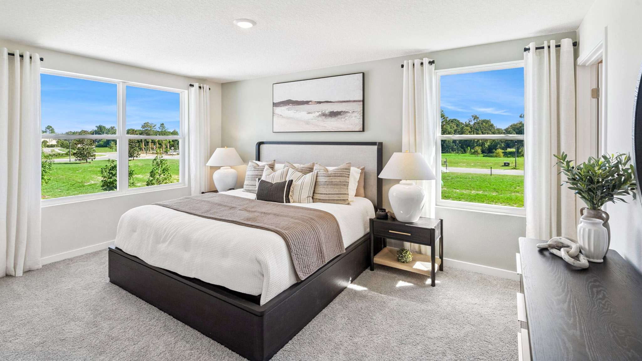 Spacious primary bedroom with king size bed, carpet flooring, natural lighting.