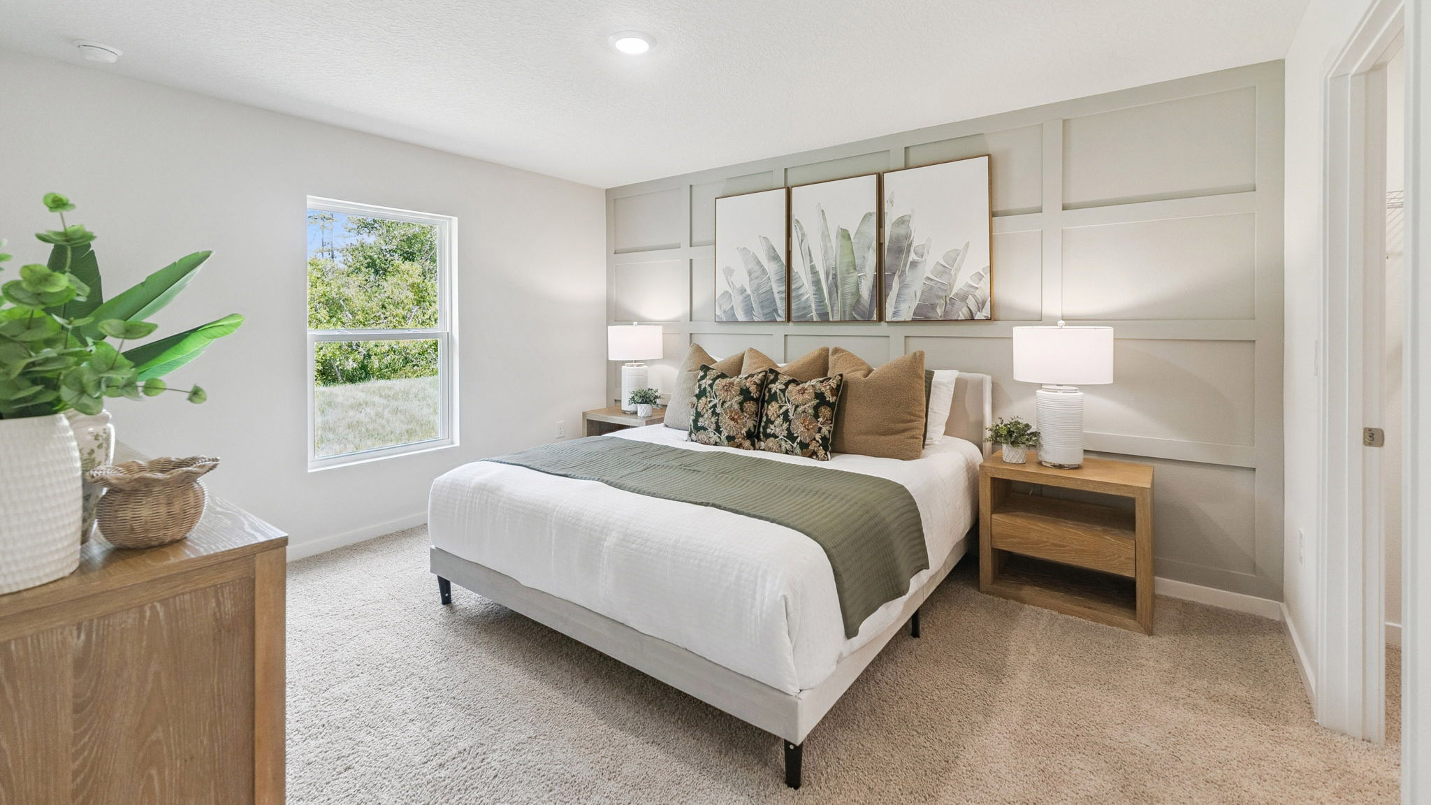 Spacious primary bedroom with king size bed, carpet flooring, natural lighting.