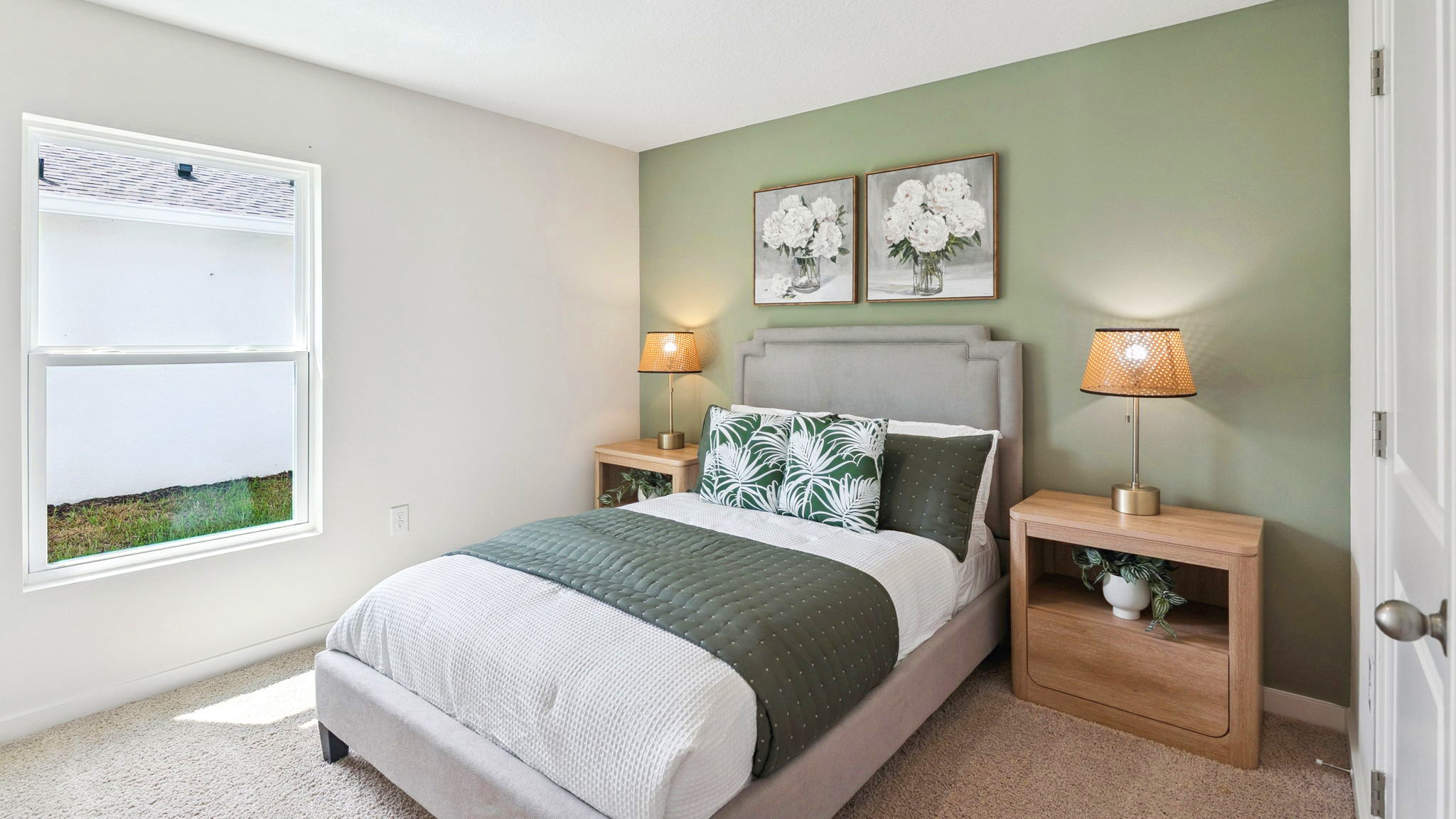 Spacious primary bedroom with king size bed, carpet flooring, natural lighting.