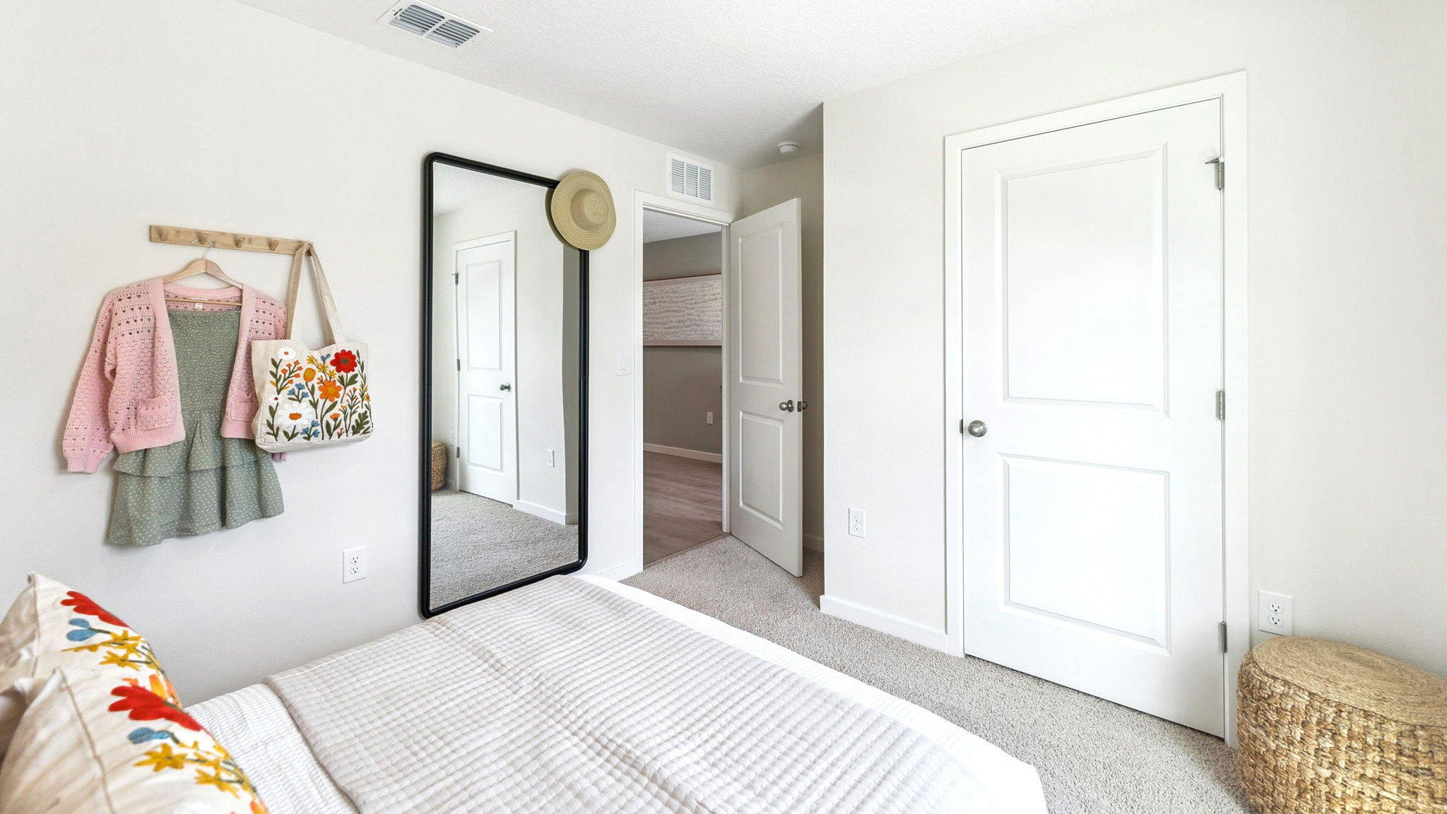 Spacious primary bedroom with king size bed, carpet flooring, natural lighting.