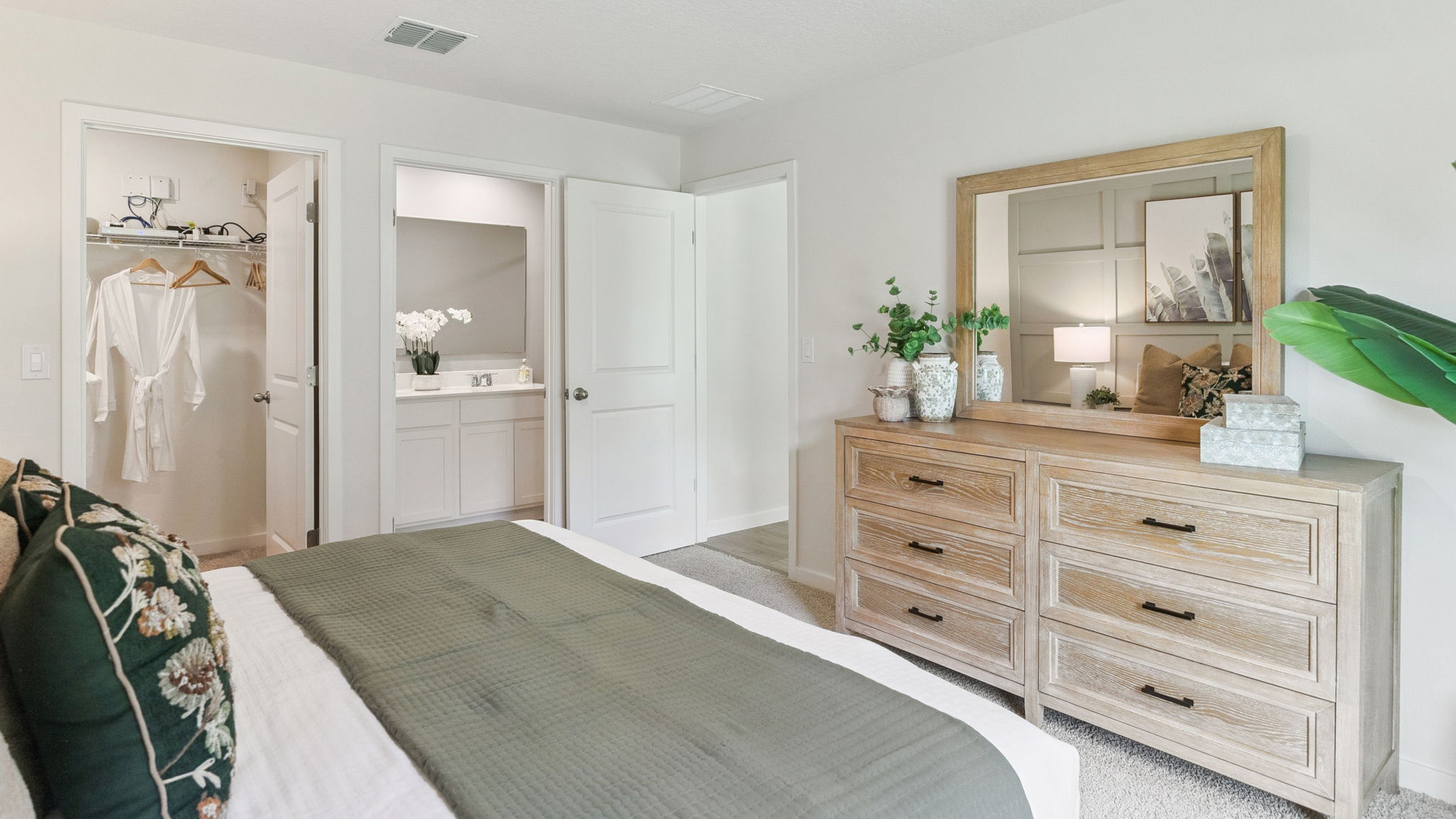 Spacious primary bedroom with king size bed, carpet flooring, natural lighting.