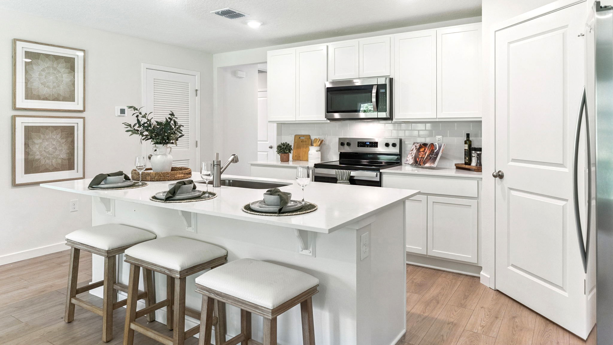 Kitchen with seating, quartz counters, spacious pantry and stainless steel appliances.