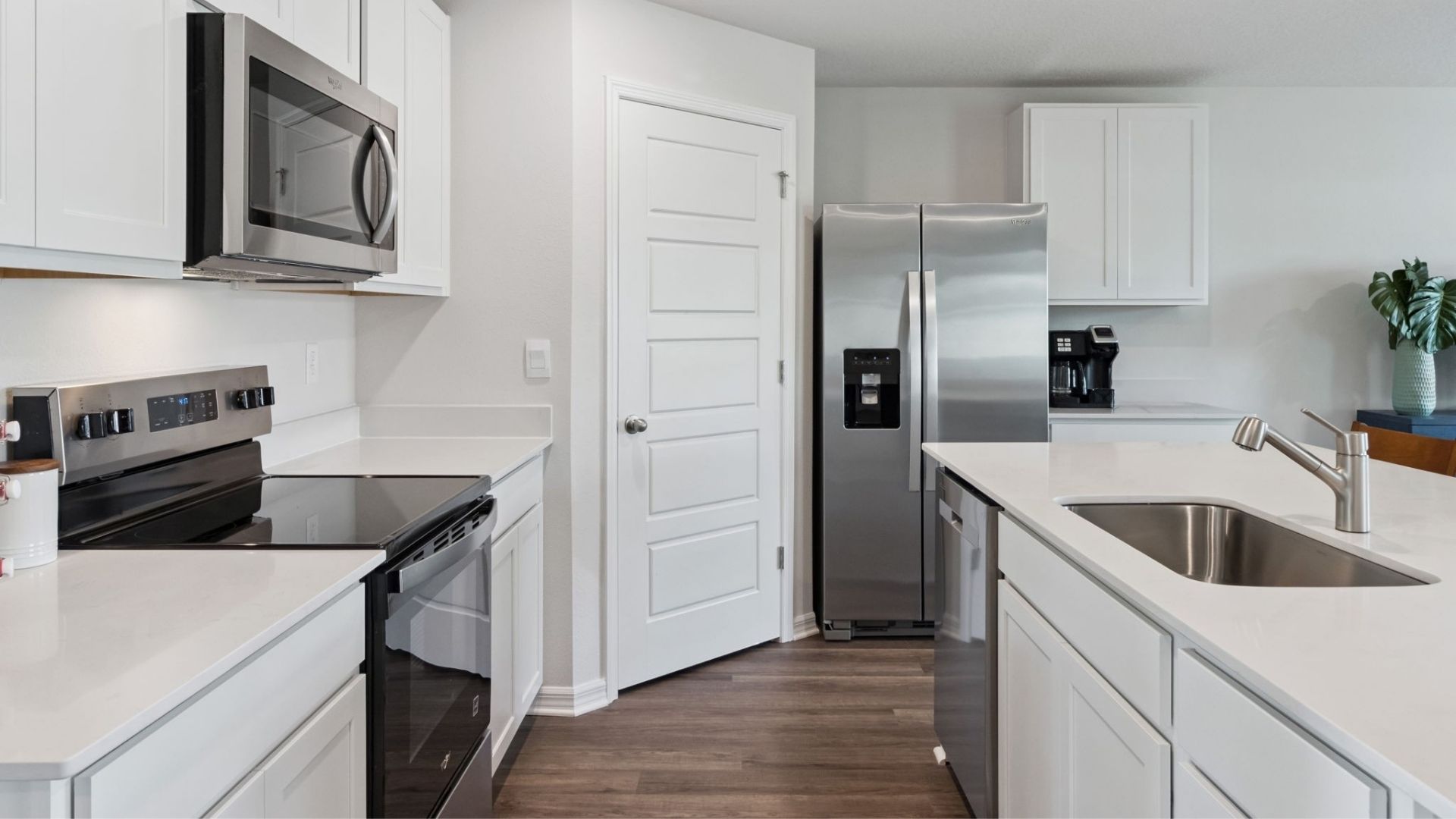 Kitchen with island seating, quartz counters, spacious pantry and stainless steel appliances.