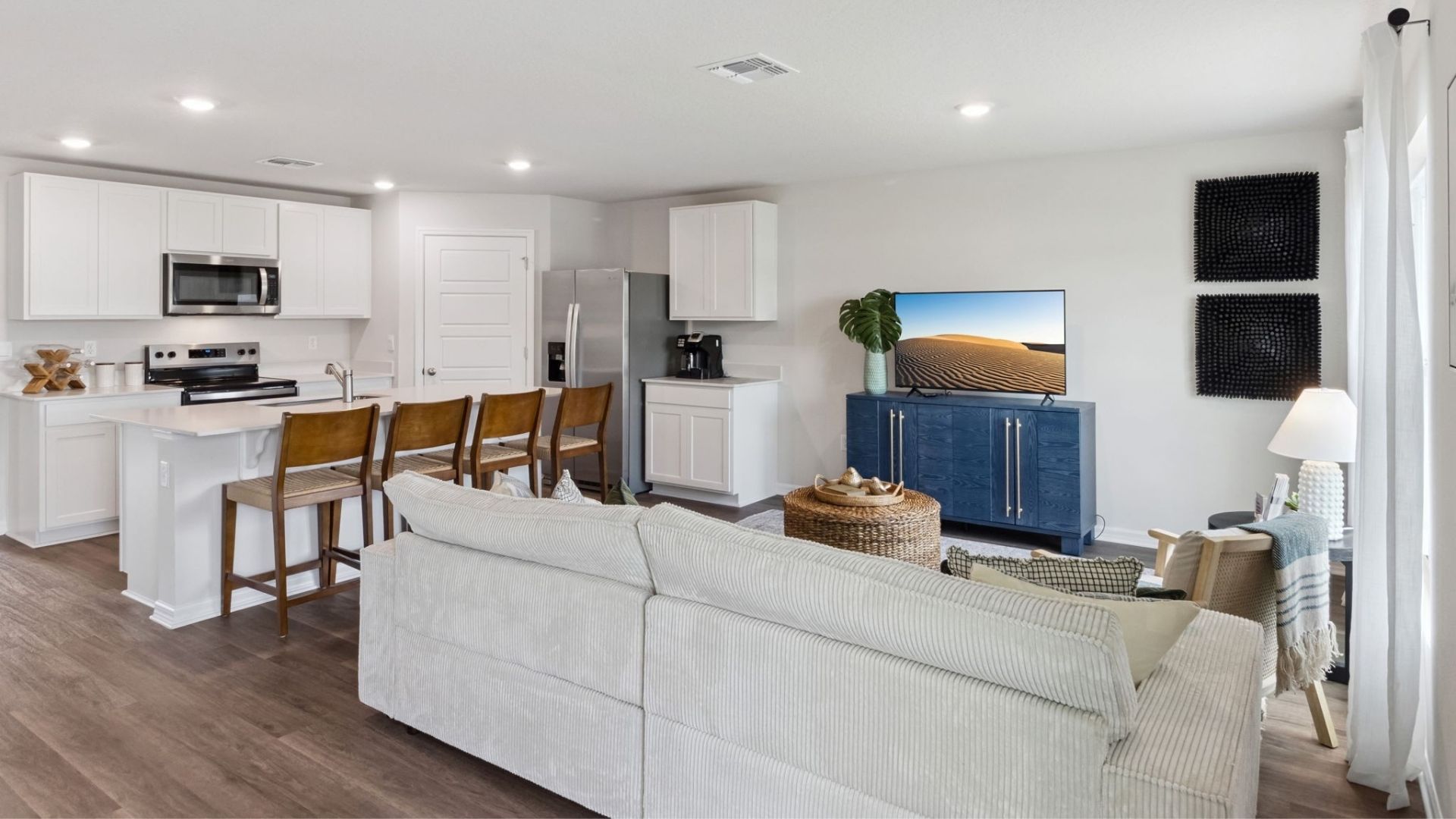 Living area with couch seating, entertainment system and natural lighting overseeing kitchen and dining room