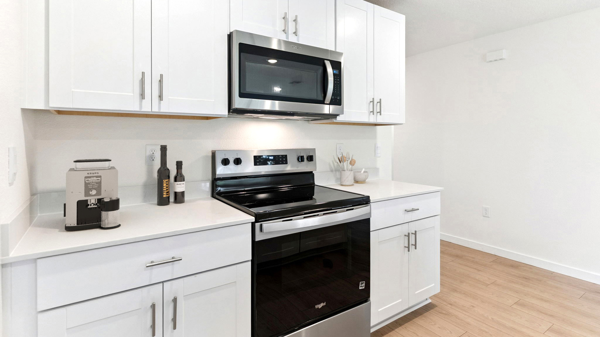 Kitchen with island seating, quartz counters, spacious pantry and stainless steel appliances.