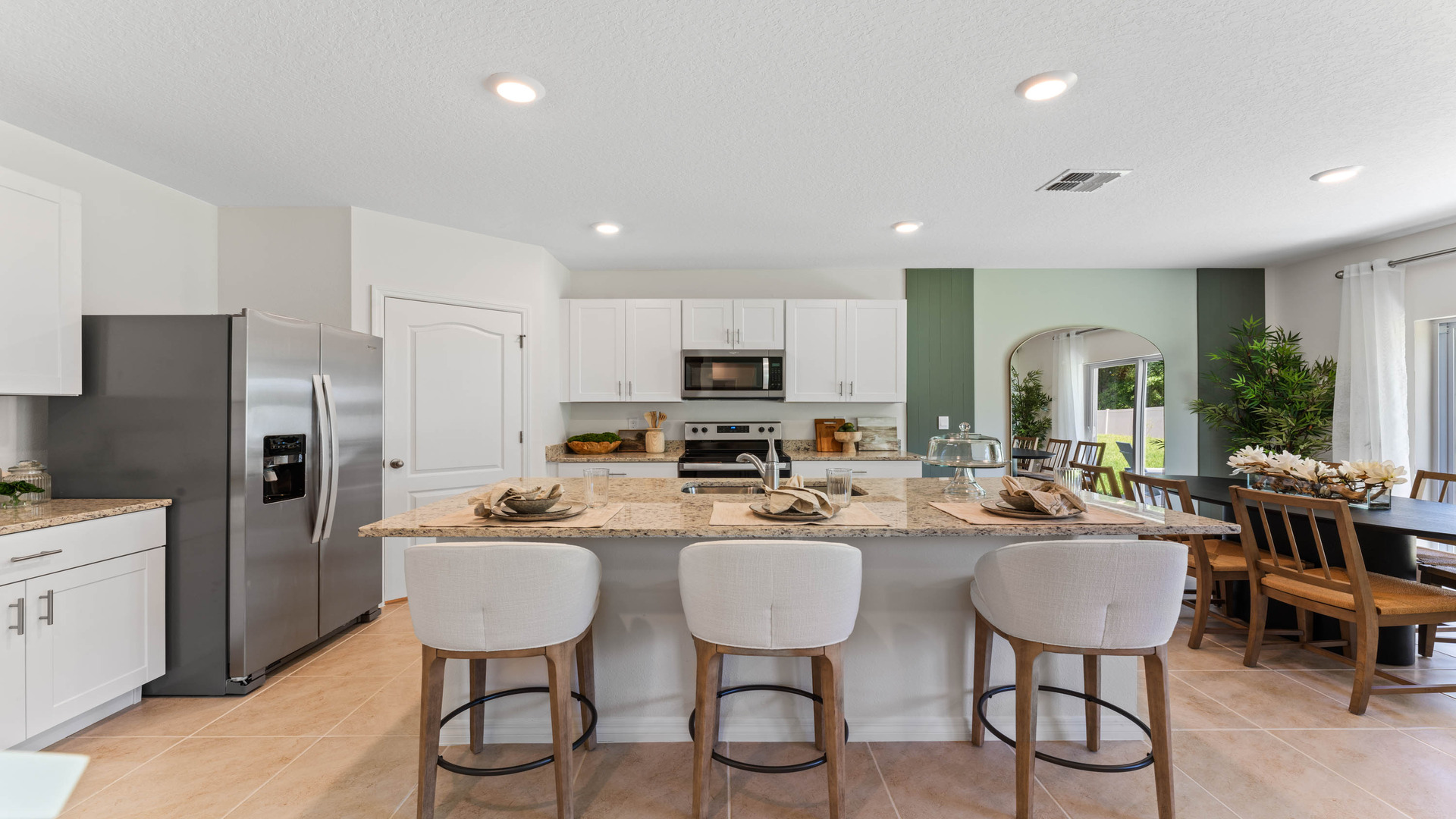 Kitchen with island seating, granite counters, spacious pantry and stainless-steel appliances.