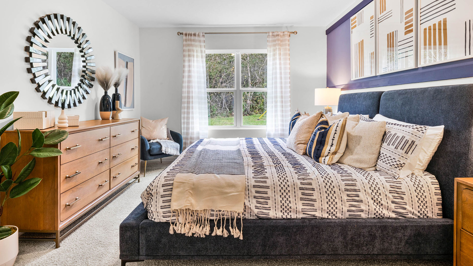 Spacious primary bedroom with king size bed, carpet flooring, natural lighting and a walk in closet.