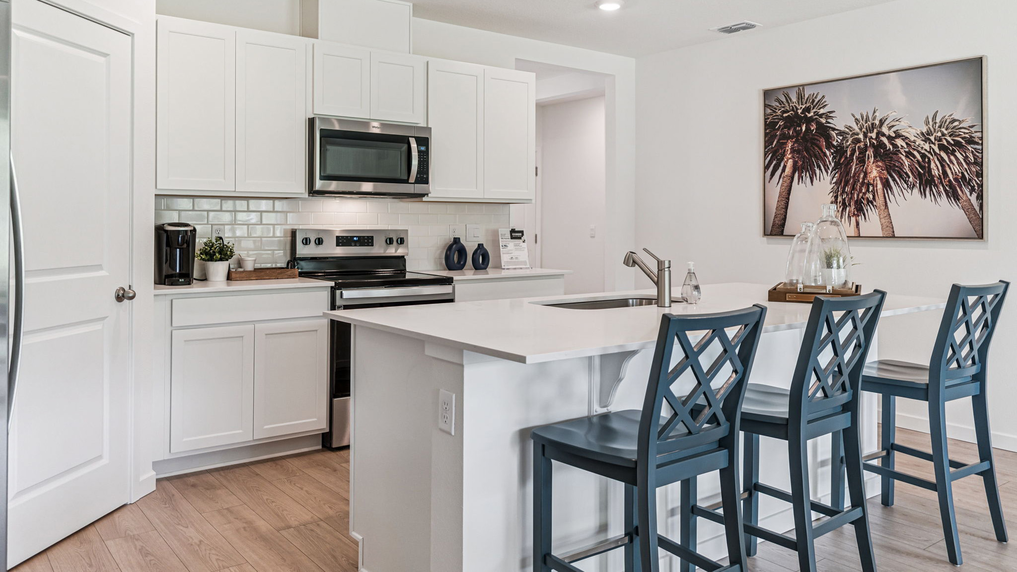 Kitchen with island seating, quartz counters, spacious pantry and stainless steel appliances overseeing living area