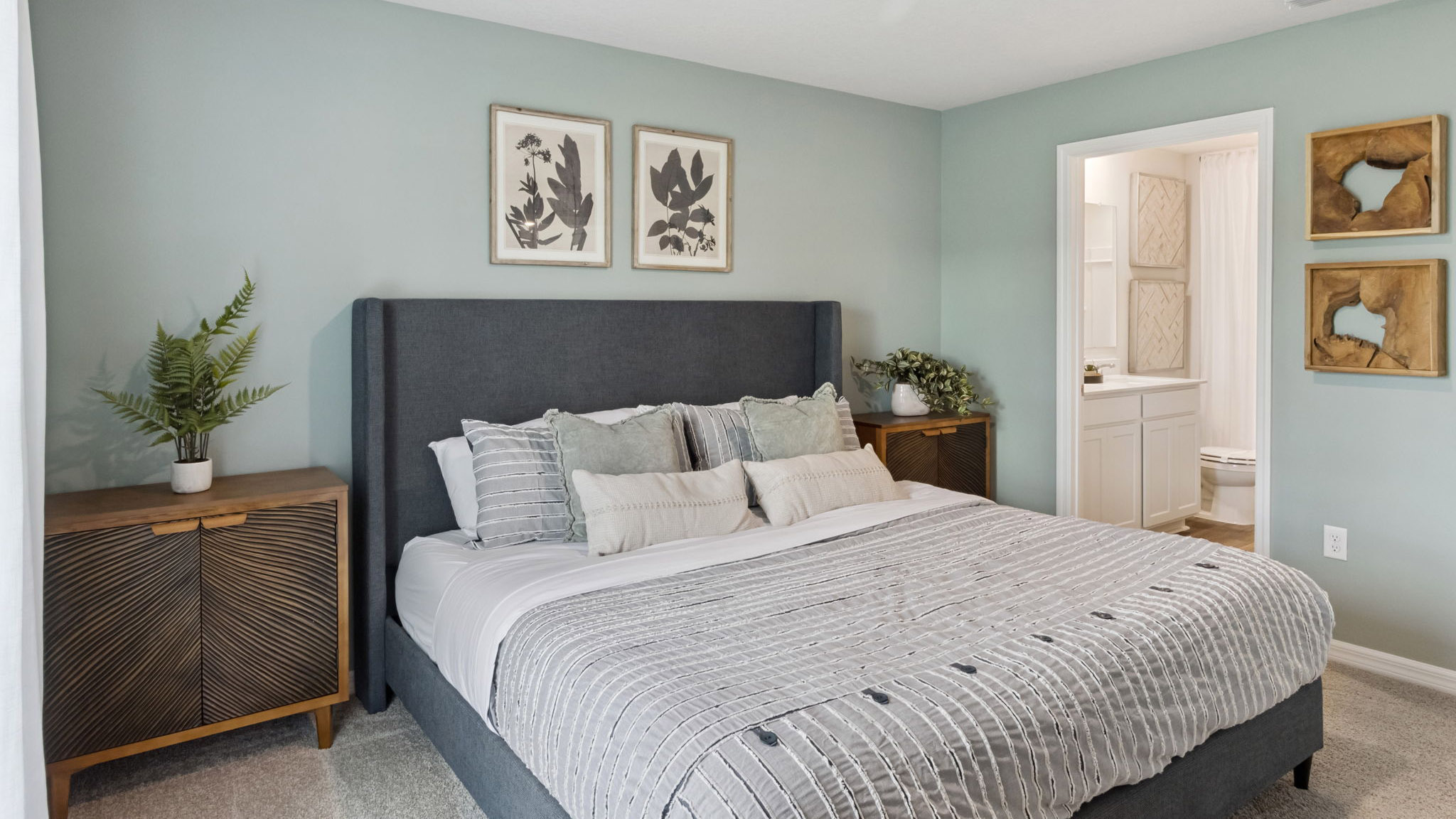 Spacious primary bedroom with king size bed, carpet flooring, natural lighting.