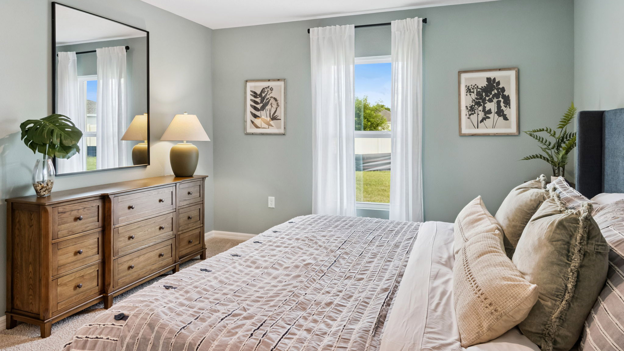 Guest bedroom with bed, nighstand, desk, and natural lighting with spacious closet.