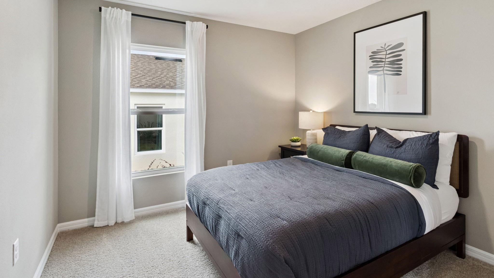 Guest bedroom with bed, nighstand, desk, and natural lighting with spacious closet.