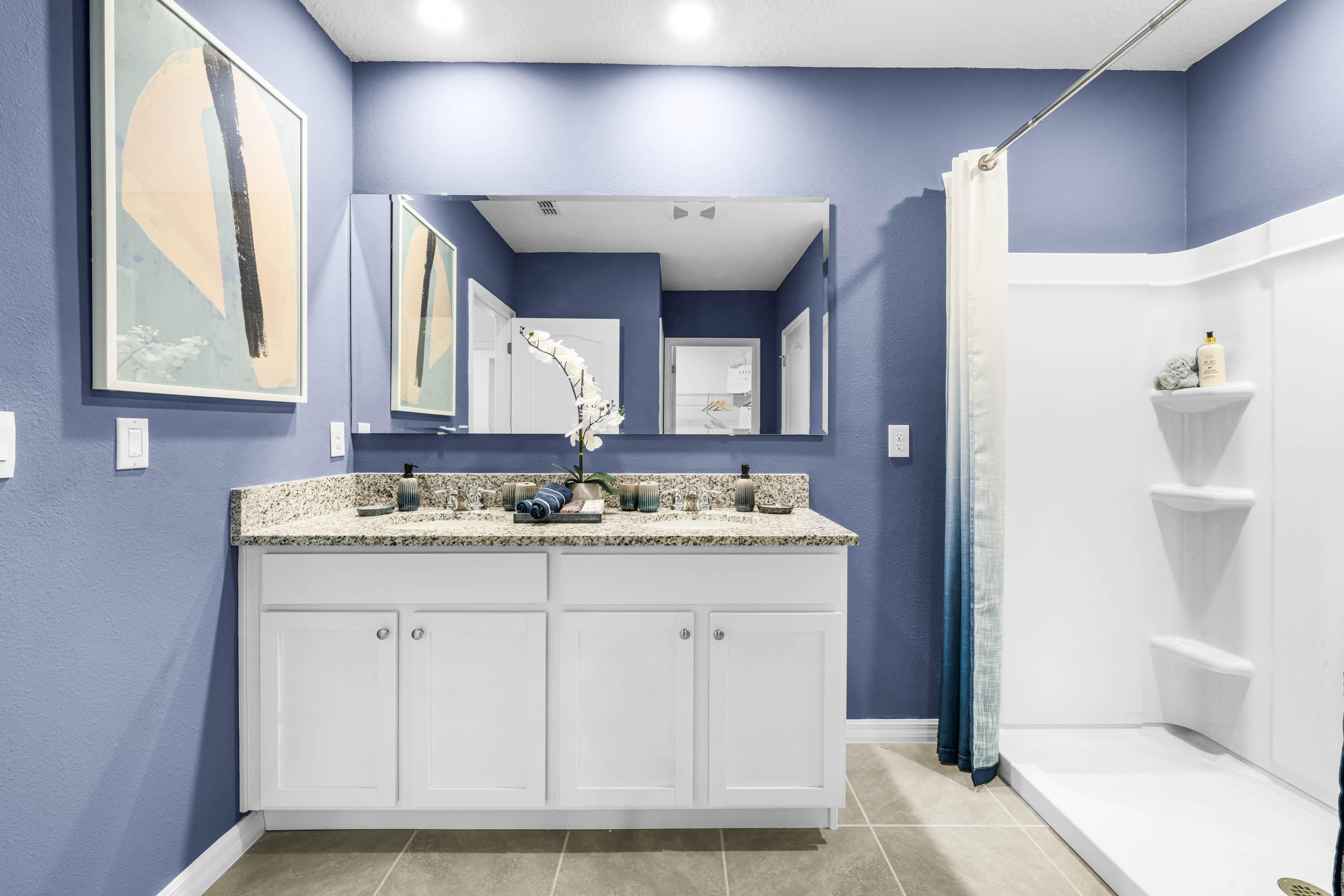 Modern bathroom with double vanity sinks, large wall mirror, cabinets and granite countertops.