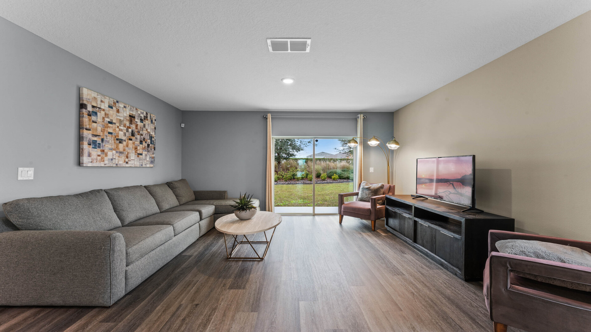 Living area with couch seating, entertainment system and natural lighting overseeing kitchen and dining room