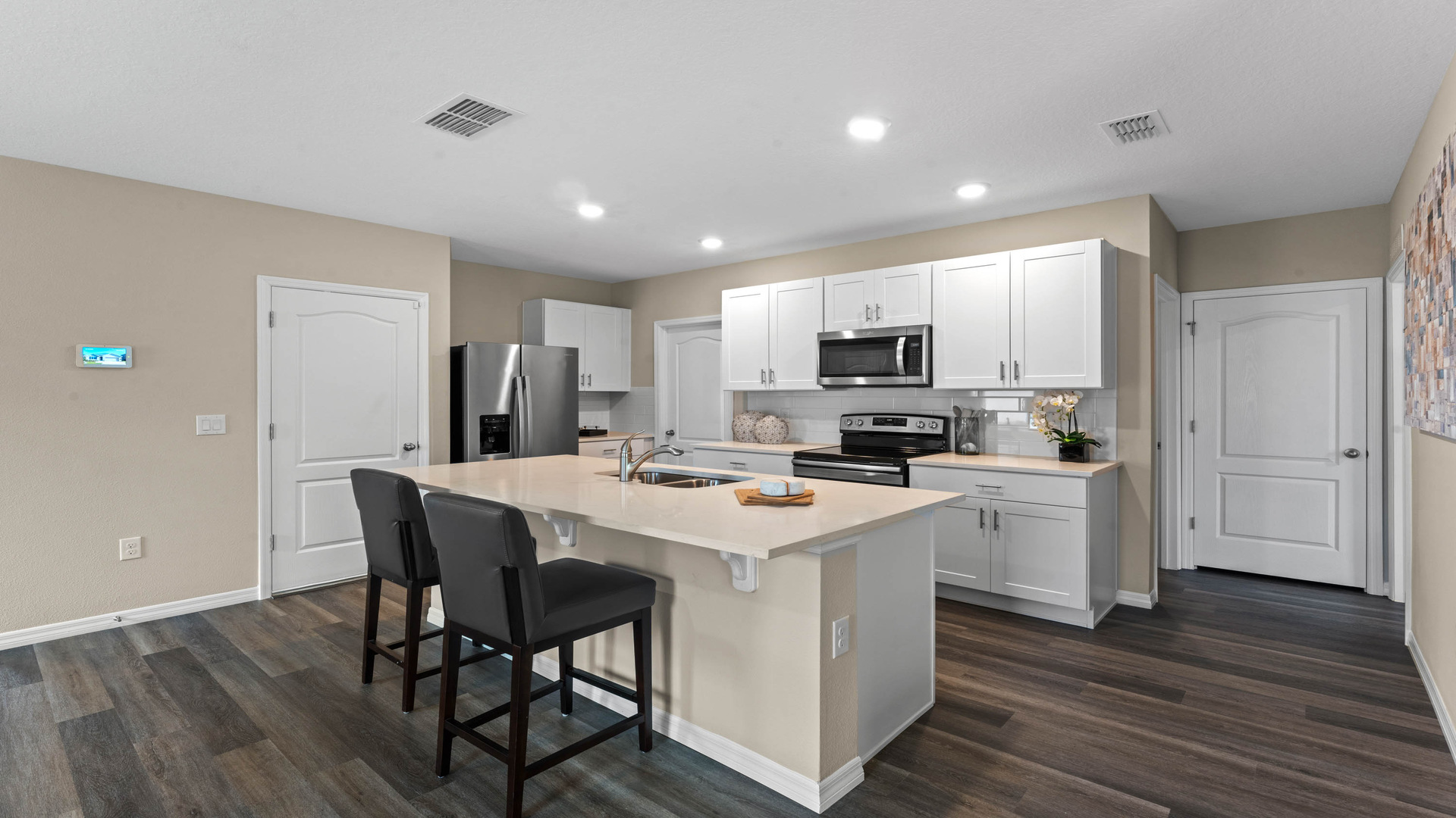 Kitchen with island seating, quartz counters, spacious pantry and stainless steel appliances showing entry way to home overseeing dining room