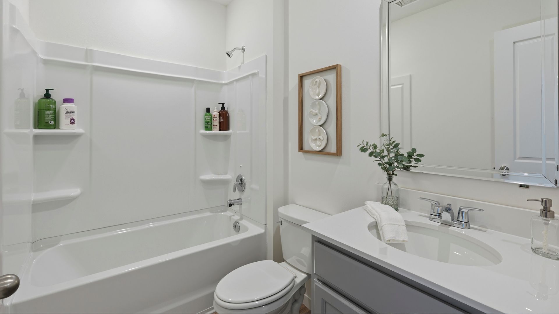 Modern bathroom with double vanity, large wall mirror, cabinets and quartz countertops along with walk-in shower