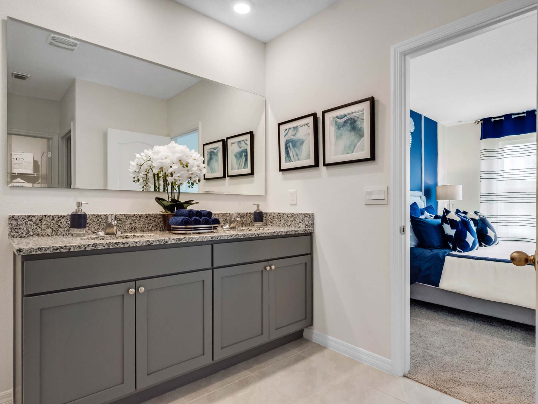 Modern bathroom with double vanity sinks, large wall mirror, cabinets and granite countertops.