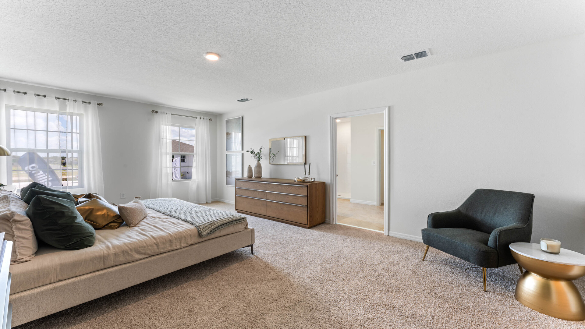 Spacious primary bedroom with king size bed, carpet flooring, natural lighting and a walk in closet.