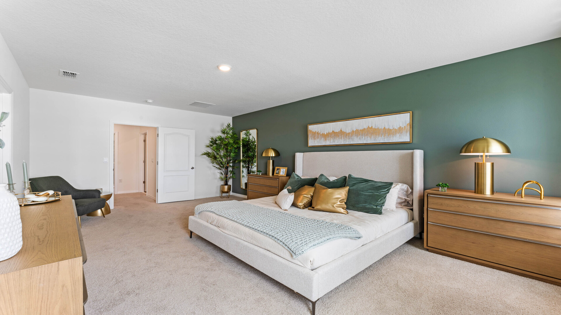 Spacious primary bedroom with king size bed, carpet flooring, natural lighting and a walk in closet.