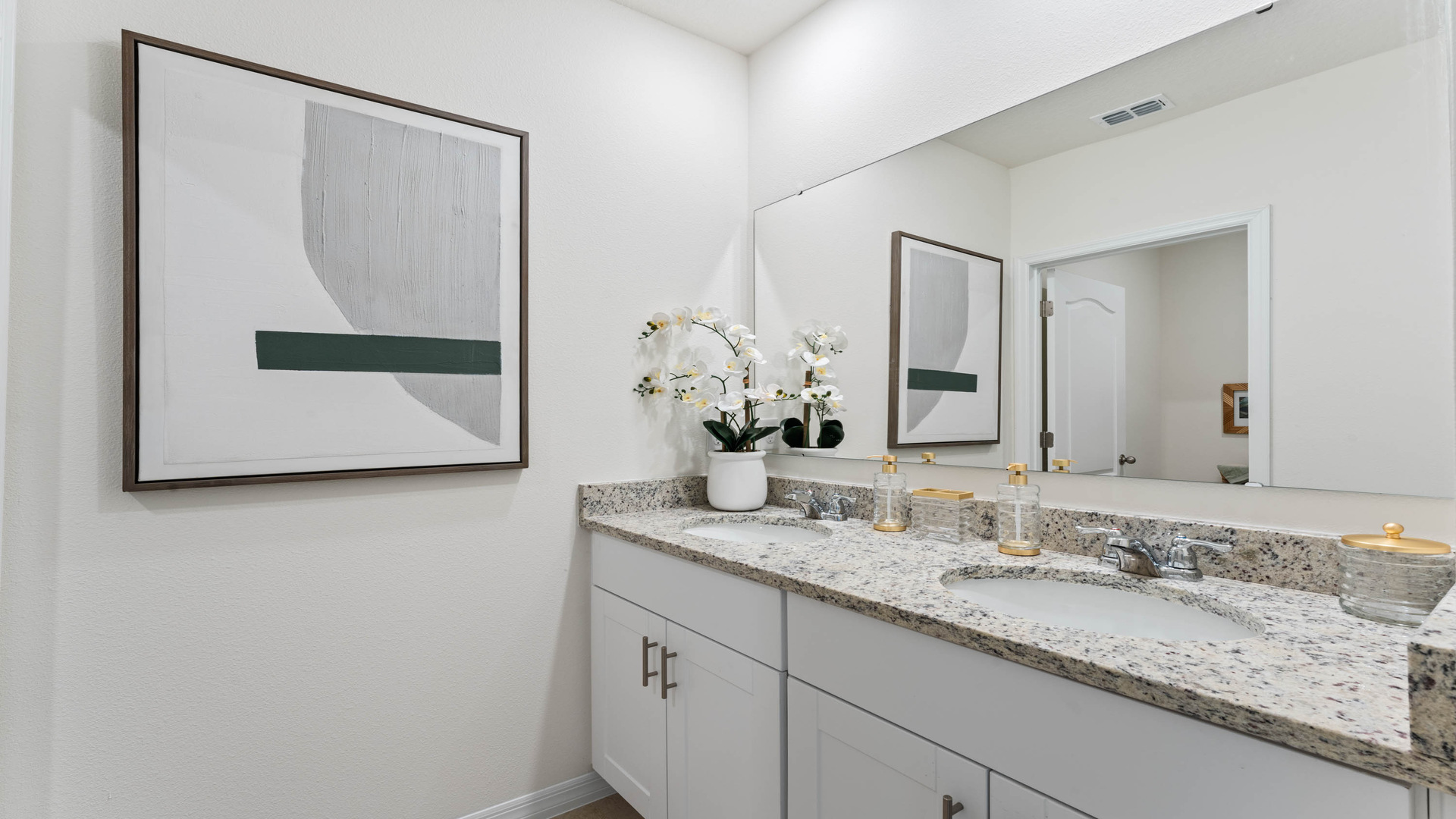 Modern bathroom with double vanity sinks, large wall mirror, cabinets and granite countertops.